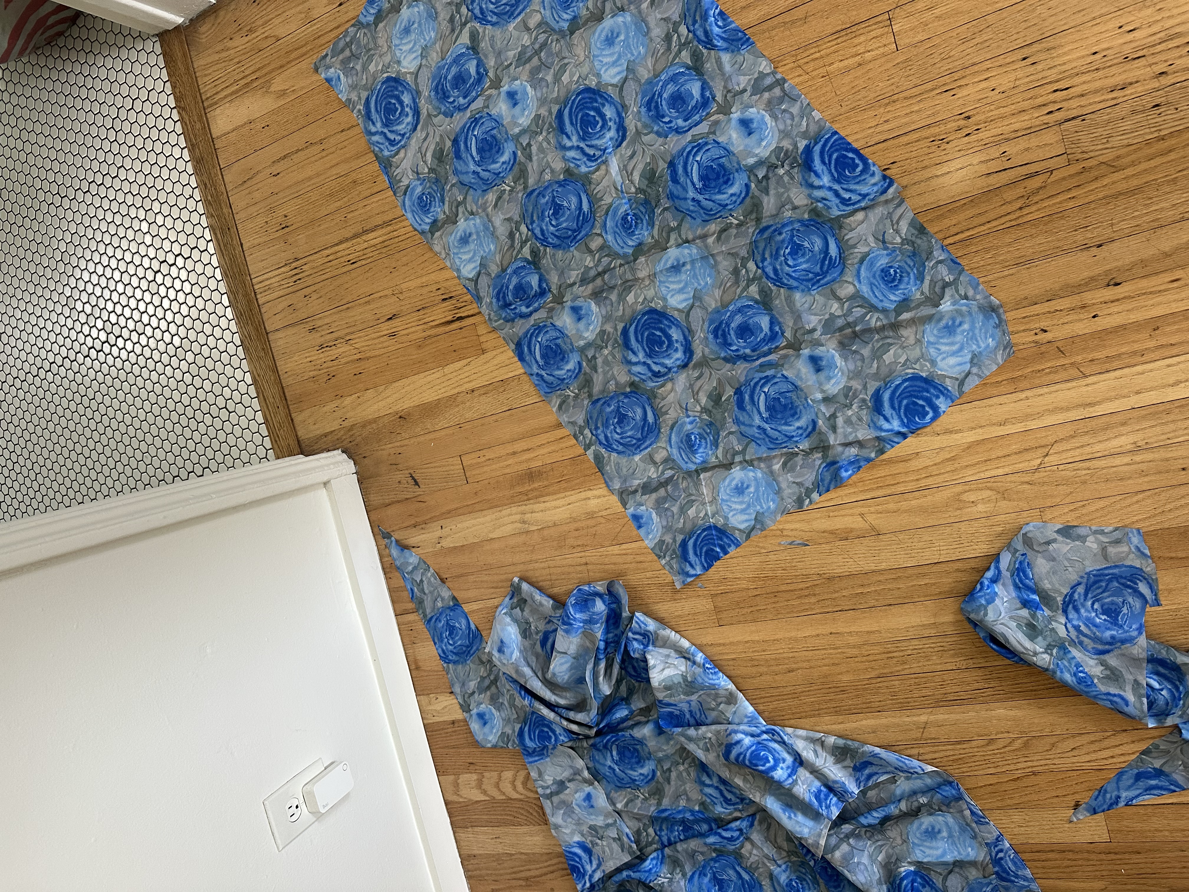 Rose print silk pieces laid out on the wood floor before cutting